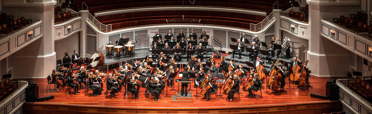 Full orchestra on stage posed fora formal photo in Palladium before a concert